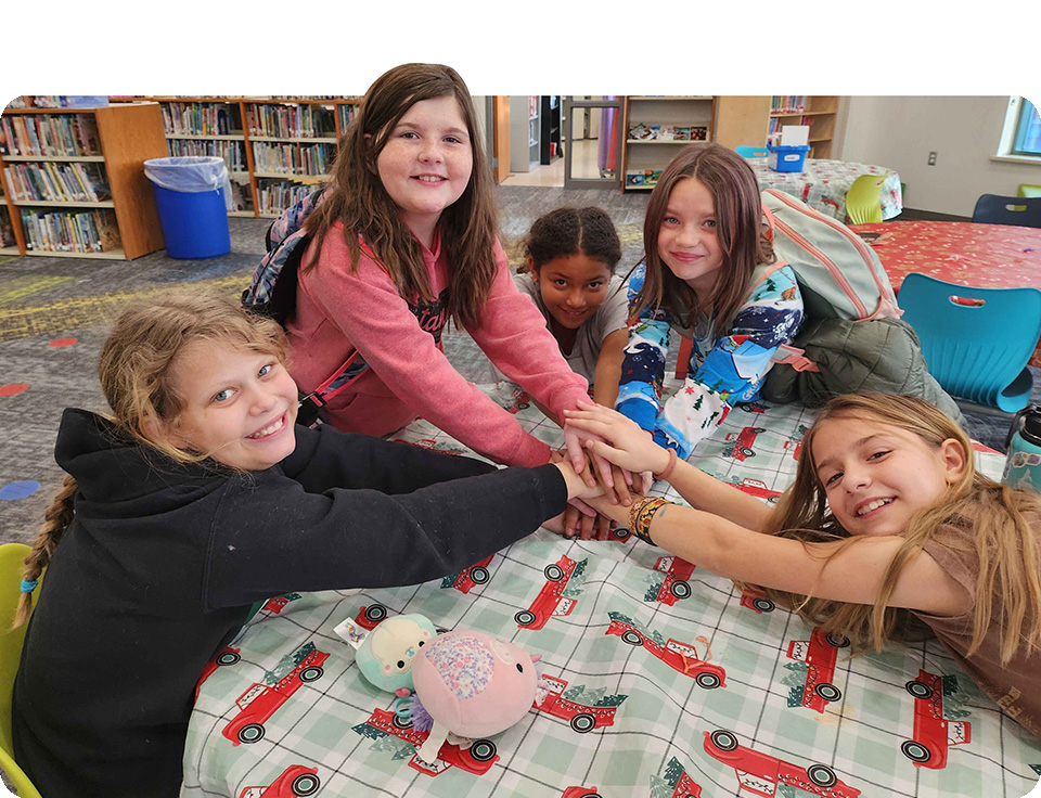 Kids reaching to stack their hands on one another.