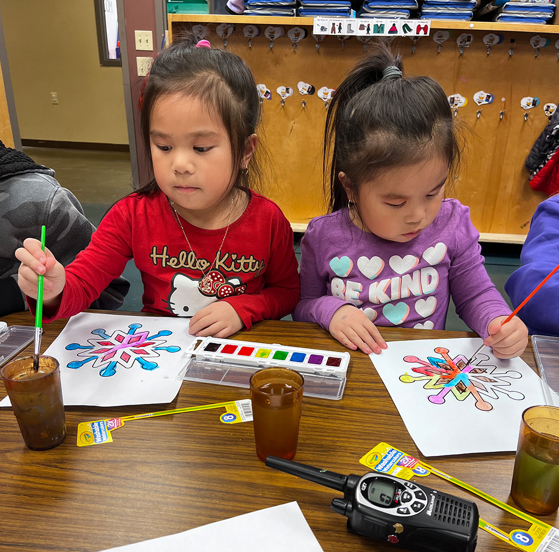 Two kids using a watercolor paint set.