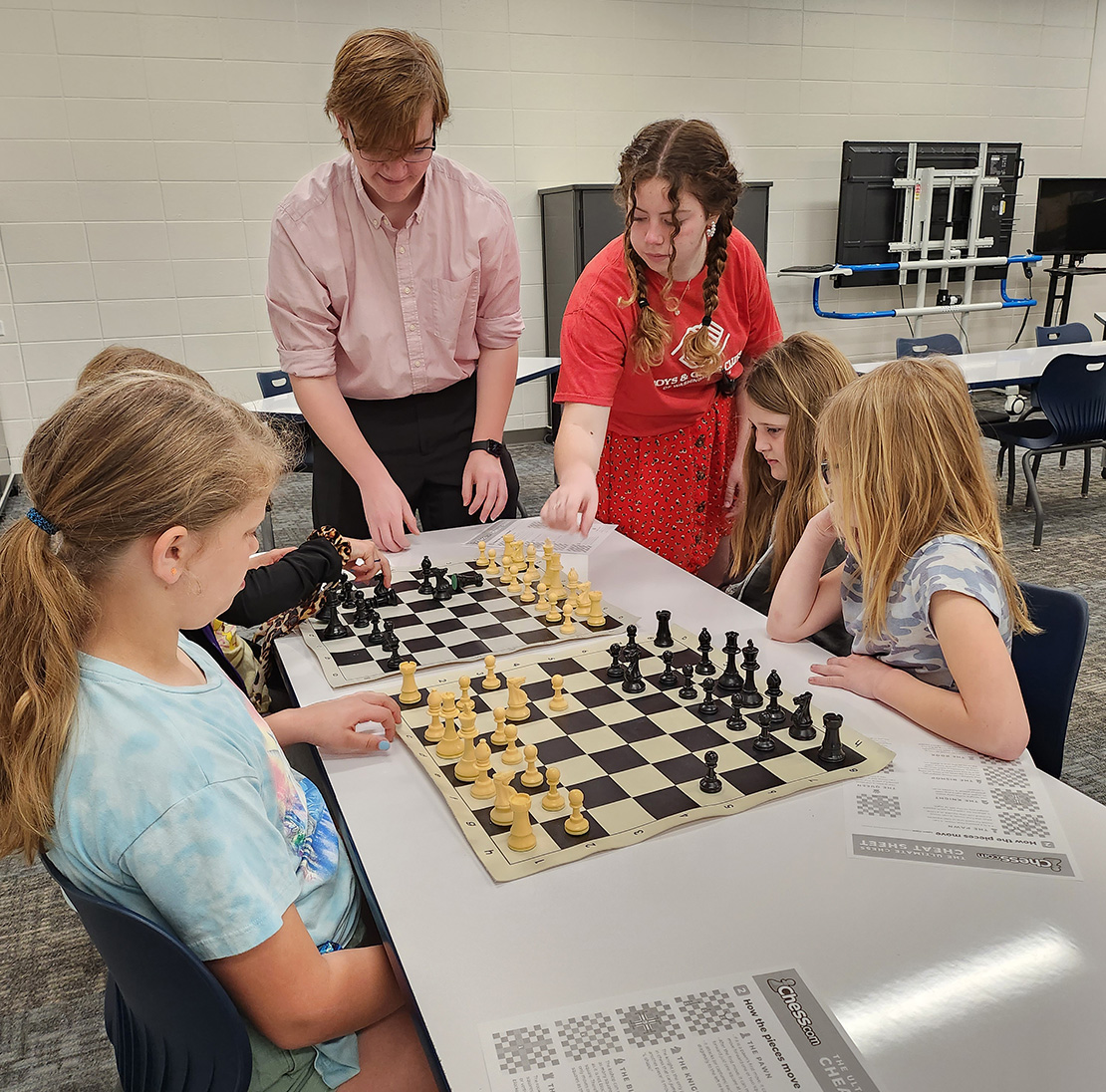 Older kids showing younger kids how to play chess.