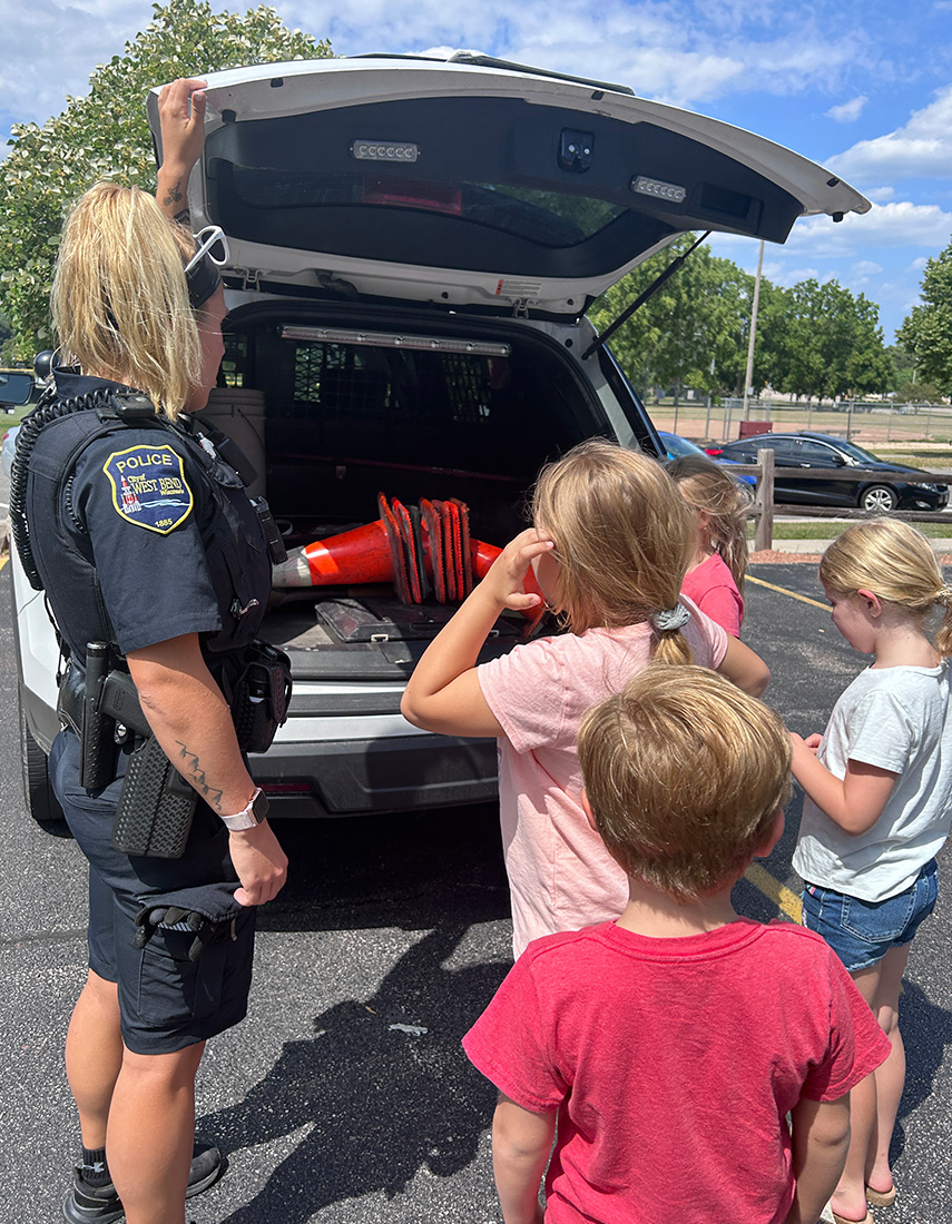 Police officer with kids showing safety equipment 