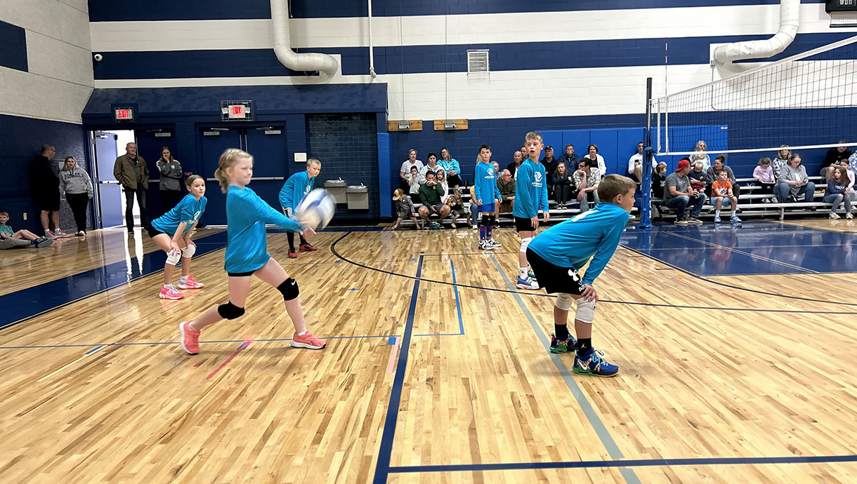 Girl serving a volleyball.